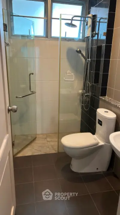 Modern bathroom with glass shower enclosure, sleek fixtures, and tiled flooring, offering a clean and contemporary living space.