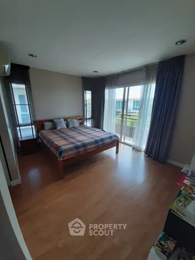 Spacious bedroom with large windows and wooden flooring, offering a bright and airy atmosphere.