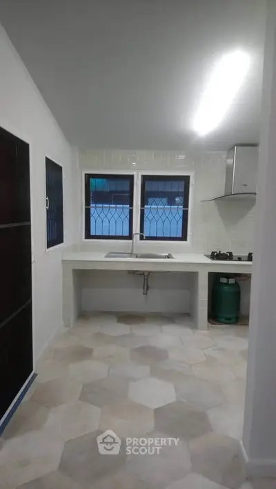 Modern kitchen with hexagonal tiles and gas stove in a bright interior.