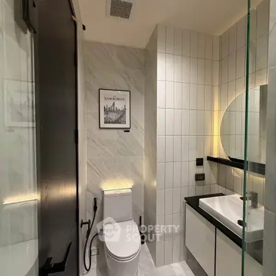 Modern bathroom with sleek design, featuring a toilet, sink, and stylish wall art.