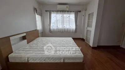 Spacious bedroom with large windows and wooden flooring, featuring a modern bed frame and ample natural light.