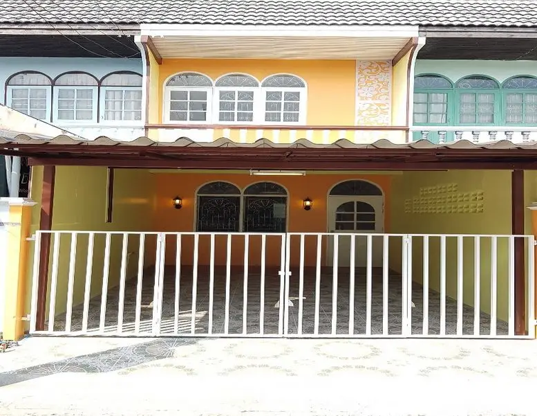 Charming townhouse with gated entrance and vibrant facade in a cozy neighborhood.