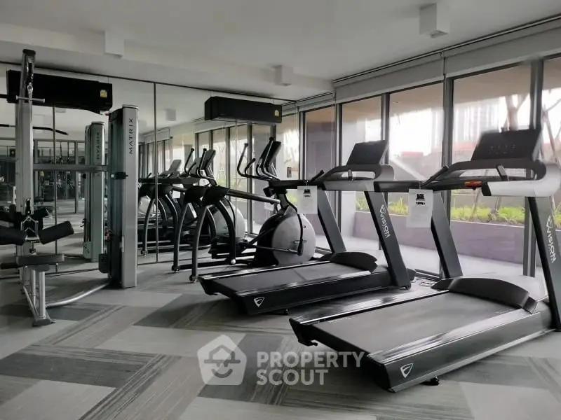 Modern gym with state-of-the-art equipment and large windows for natural light.