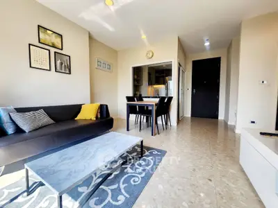 Modern living room with stylish decor and open kitchen layout, featuring a cozy sofa and elegant dining area.
