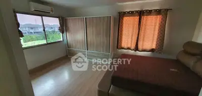Spacious bedroom with large window and modern wardrobe in a cozy home.