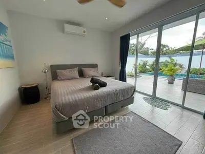 Spacious bedroom with pool view and modern decor, perfect for relaxation.