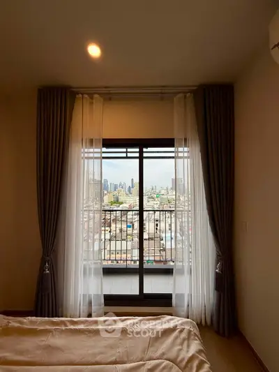 Cozy bedroom with city view from large window, featuring elegant curtains and soft lighting.