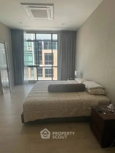 Spacious bedroom with large windows and modern decor in a luxury apartment.