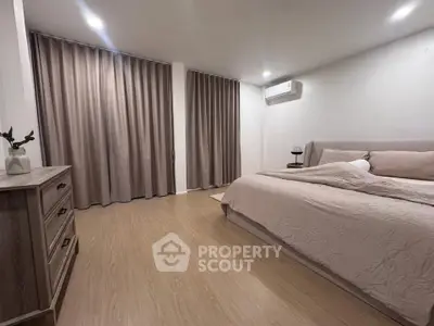 Spacious bedroom with modern decor and natural light, featuring elegant curtains and a cozy bed.