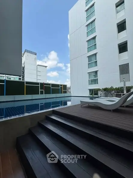 Modern apartment pool area with city view and lounge chairs