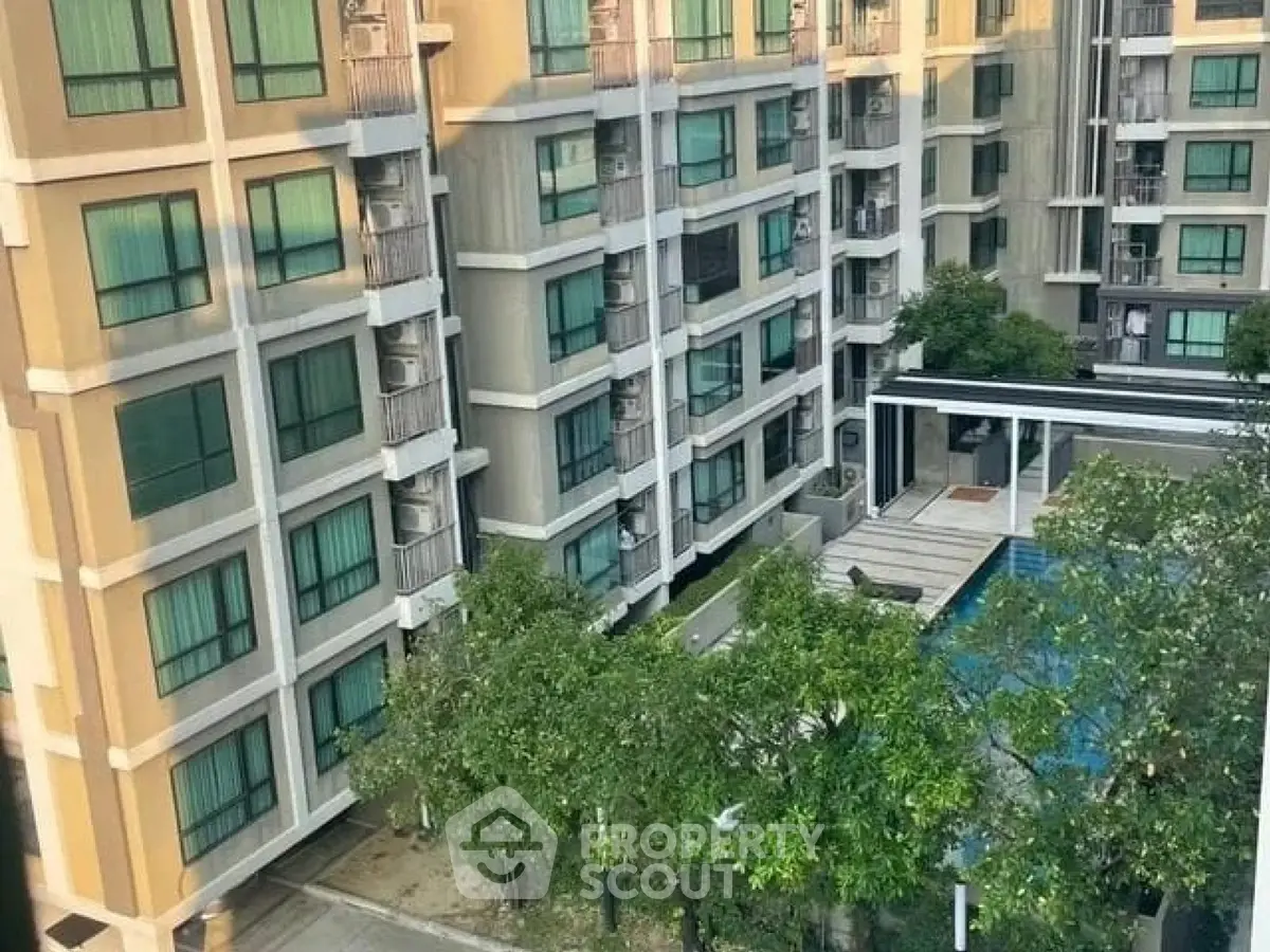 Modern apartment building with pool and lush greenery in urban setting.