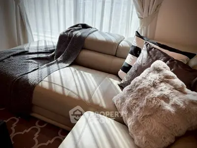 Cozy living room with plush pillows and soft throw on a stylish leather sofa, bathed in natural light.