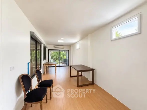 Spacious modern living room with wooden flooring and elegant chairs, perfect for stylish living.
