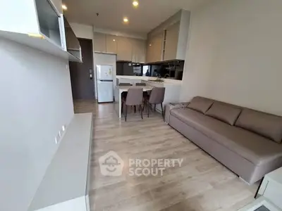 Modern open-plan living room with kitchen, featuring sleek furniture and wooden flooring.