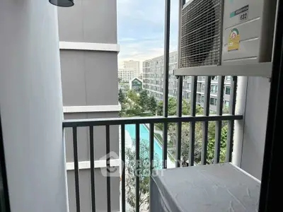 Charming balcony view overlooking modern apartment complex with pool and lush greenery.