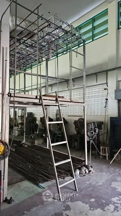 Industrial workshop space with mezzanine and ladder, ideal for creative projects.
