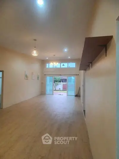 Spacious open living area with large windows and wooden flooring, perfect for modern living.