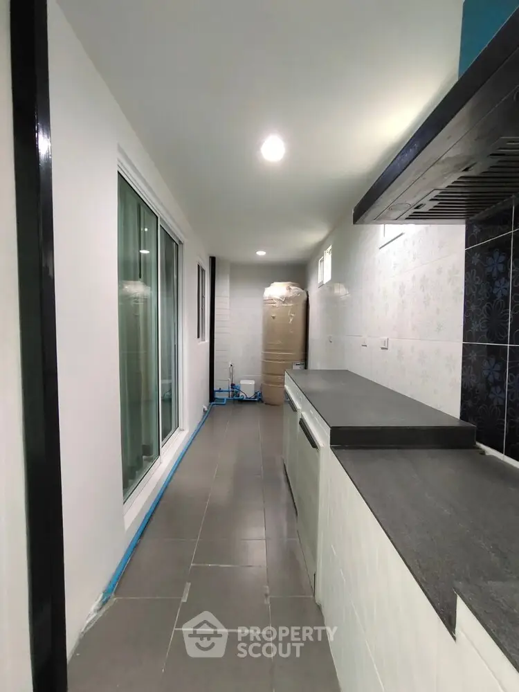 Modern kitchen with sleek countertops and sliding glass doors in a narrow layout.