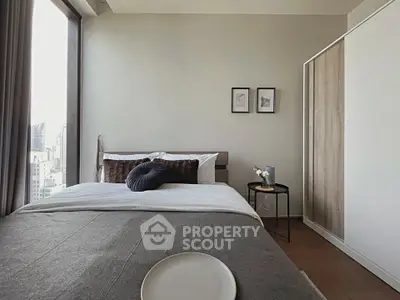 Modern bedroom with city view, featuring stylish decor and ample natural light.