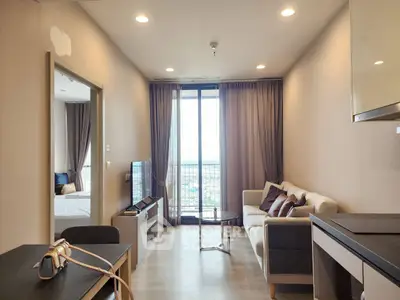 Modern living room with large windows and cozy furniture in a high-rise apartment.