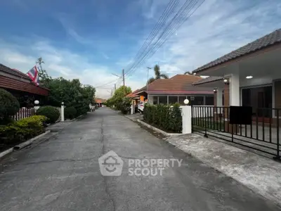 Charming residential street with modern houses and lush greenery under a clear blue sky.