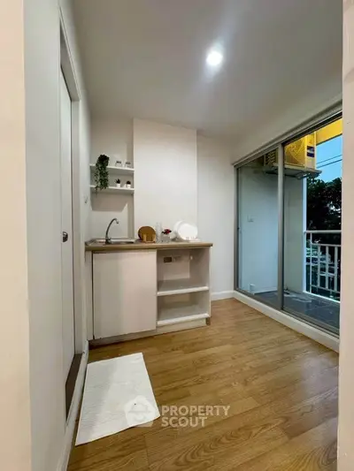 Modern compact kitchen with wooden flooring and balcony access