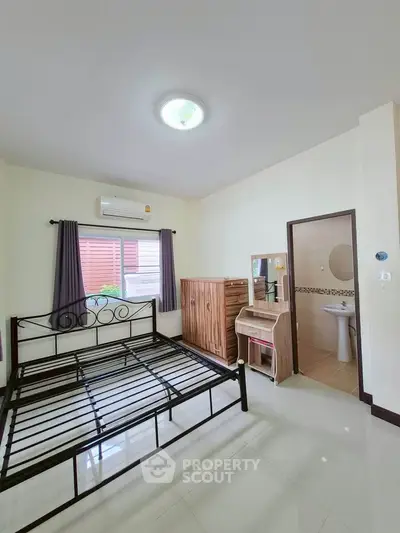 Spacious bedroom with metal bed frame and modern furniture, featuring air conditioning and natural light.