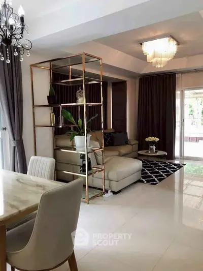 Elegant living room with modern decor and natural light, featuring a cozy seating area and stylish chandelier.