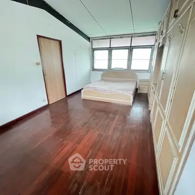 Spacious bedroom with wooden flooring and large wardrobe