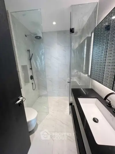 Modern bathroom with sleek design, glass shower, and elegant fixtures.