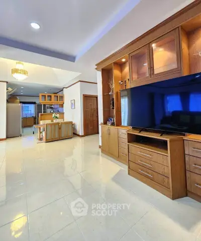 Spacious living room with built-in wooden entertainment center and open kitchen layout
