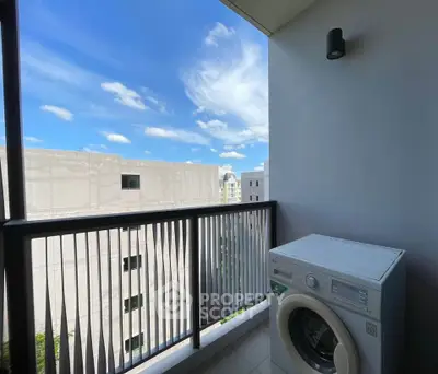 Modern balcony with washing machine and city view under clear blue sky.