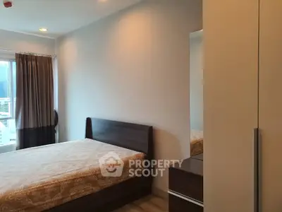 Modern bedroom with wooden furniture and large window offering natural light.