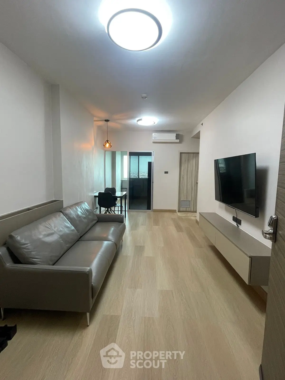 Modern living room with sleek furniture and wall-mounted TV, featuring a minimalist design.
