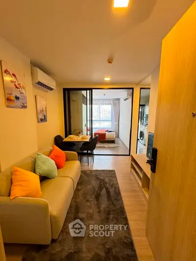Modern apartment interior with cozy living room and view into bedroom, featuring stylish decor and open layout.