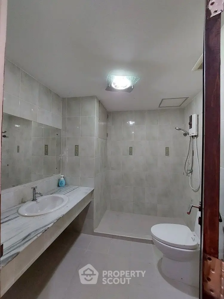 Modern bathroom with sleek tiles and spacious shower area.