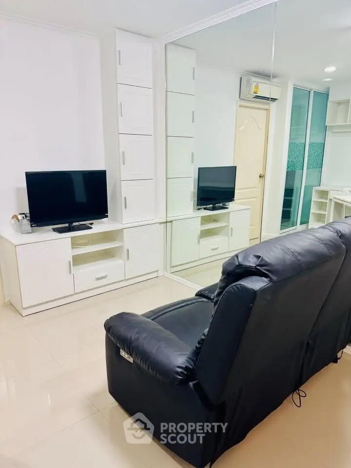 Modern living room with sleek black leather sofa and mirrored wall enhancing space and light.