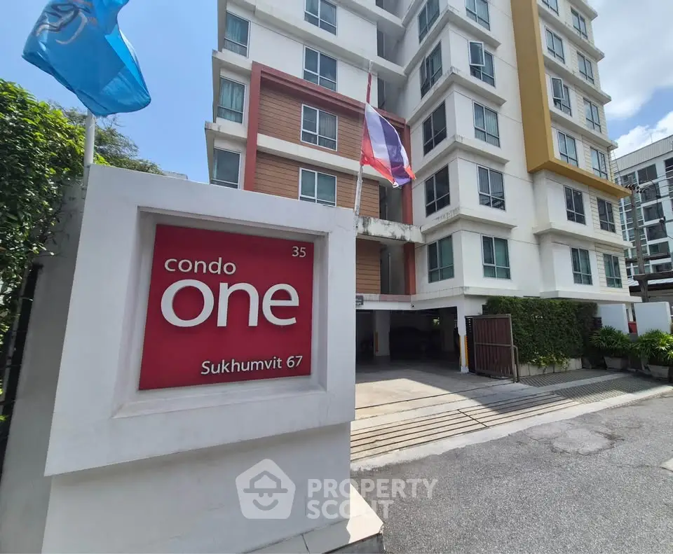 Modern condo building entrance with flags and signage at Sukhumvit 67