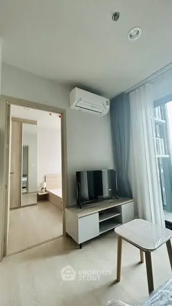 Modern apartment interior with TV, air conditioning, and balcony view.