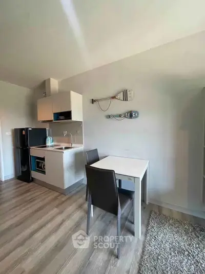 Modern compact kitchen with dining area in a cozy apartment, featuring sleek appliances and stylish decor.