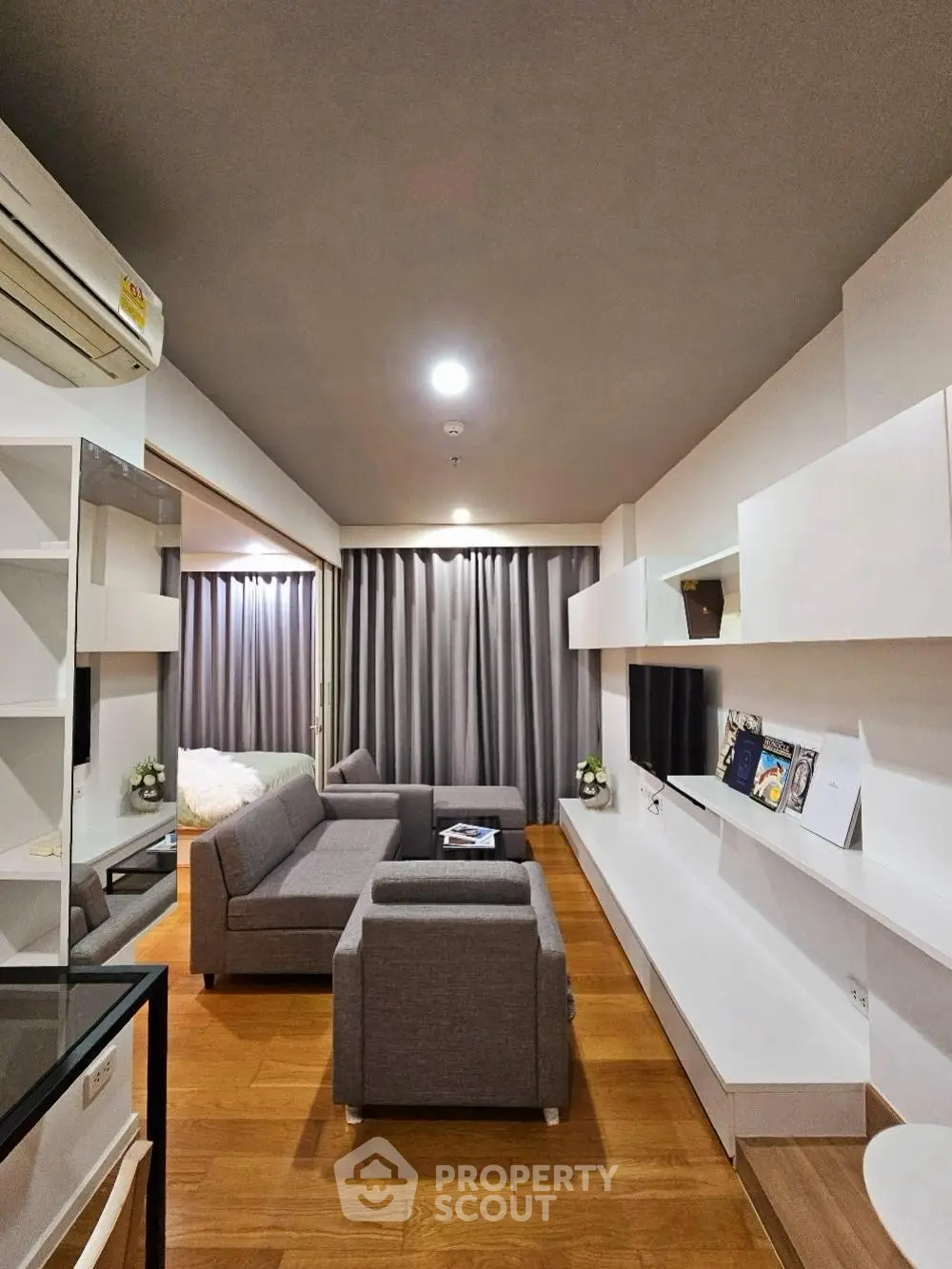 Modern living room with sleek furniture and wooden flooring in a cozy apartment setting.
