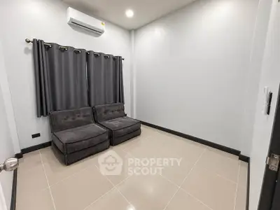 Modern minimalist living room with sleek tile flooring and cozy seating area.