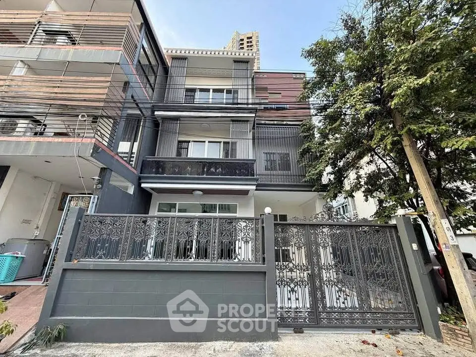 Modern multi-story townhouse with decorative gate and urban surroundings