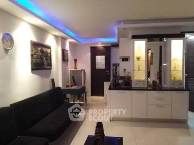 Modern living room with sleek design and ambient lighting, featuring a stylish black sofa and elegant decor.