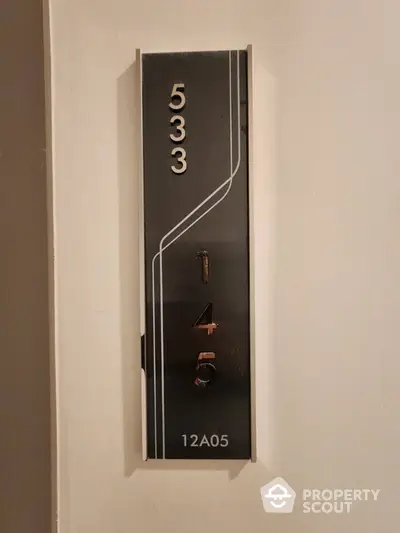 Modern apartment number plaque with sleek design and metallic numbers