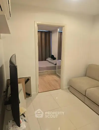 Cozy living room with modern TV setup leading to a serene bedroom, perfect for relaxation.
