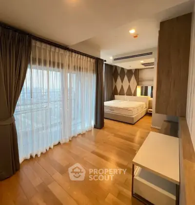 Spacious bedroom with wooden flooring and large windows offering city views.