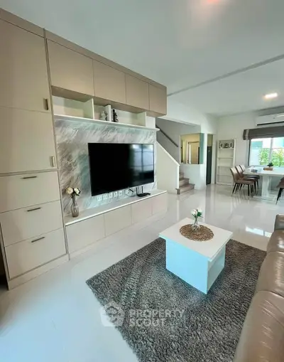 Modern living room with sleek design, featuring built-in storage, flat-screen TV, and cozy seating area.