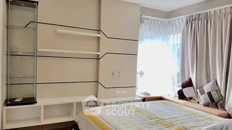 Cozy bedroom with large window and modern shelving unit, perfect for relaxation and comfort.