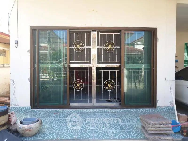 Charming home entrance with decorative metal door and tiled patio